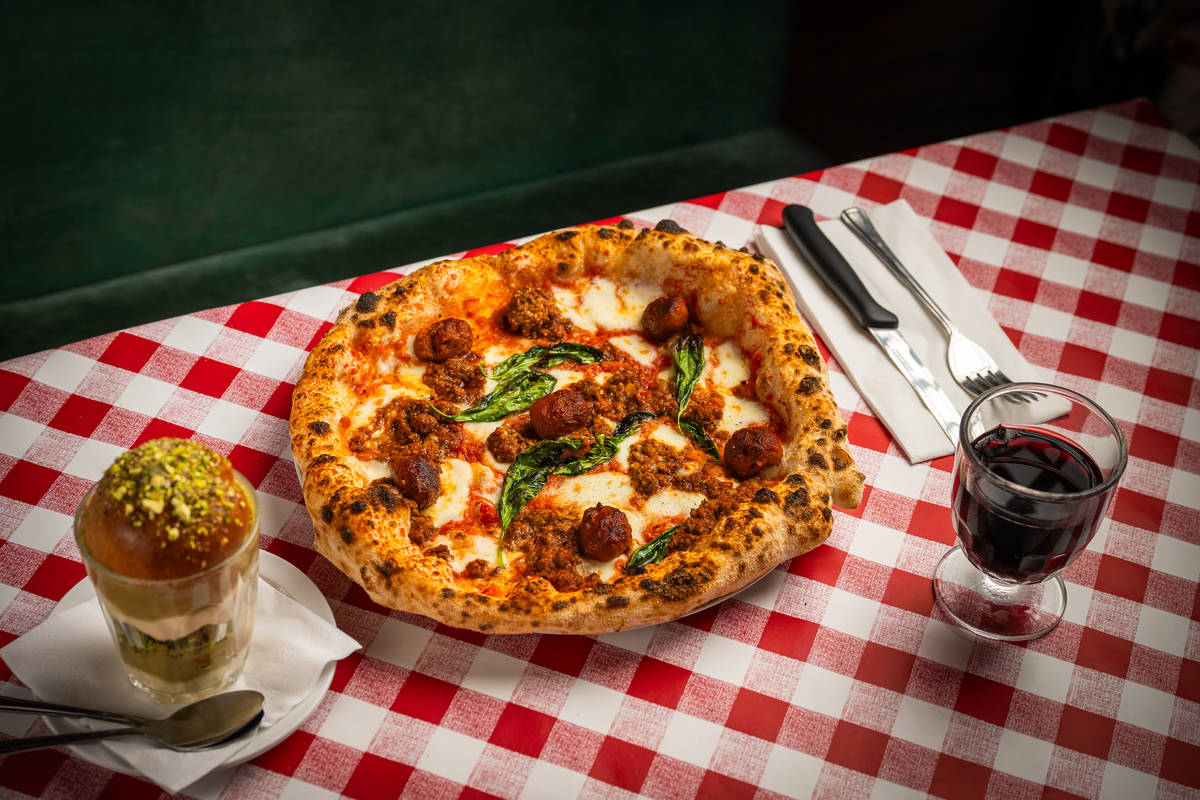 a meatball topped pizza on a checkered red and white tablecloth, next to a rum babe/tiramisu mash-up dessert and a glass of wine