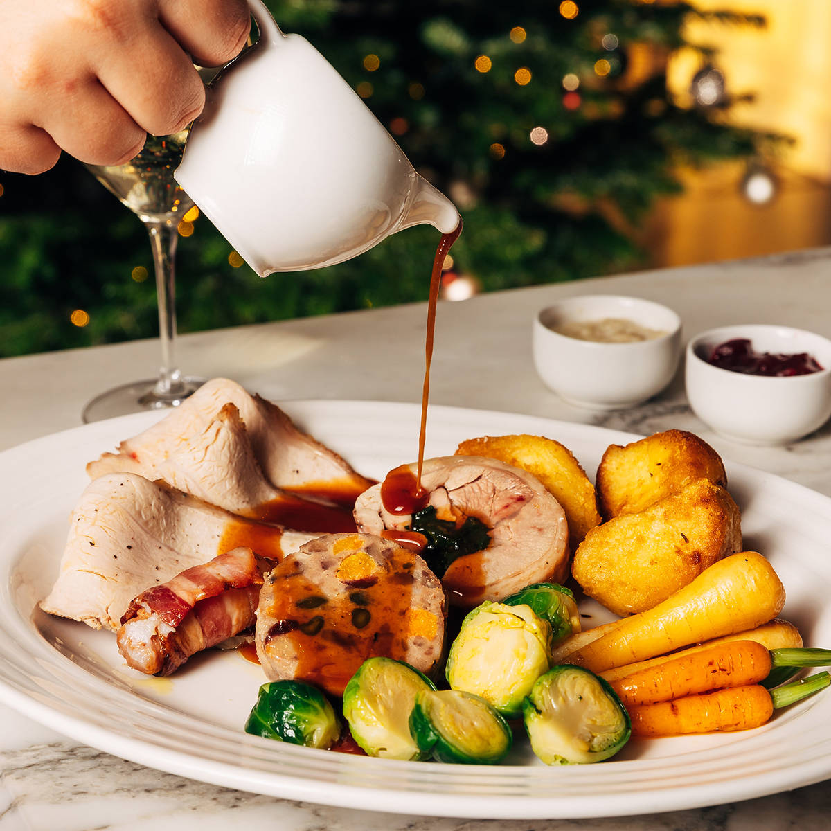 gravy being poured over a christmas dinner of turkey and roasted veg
