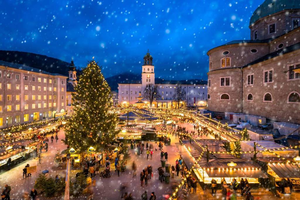 People visiting a traditional Christmas market in front of Salzburg Cathedral at the Residenzplatz