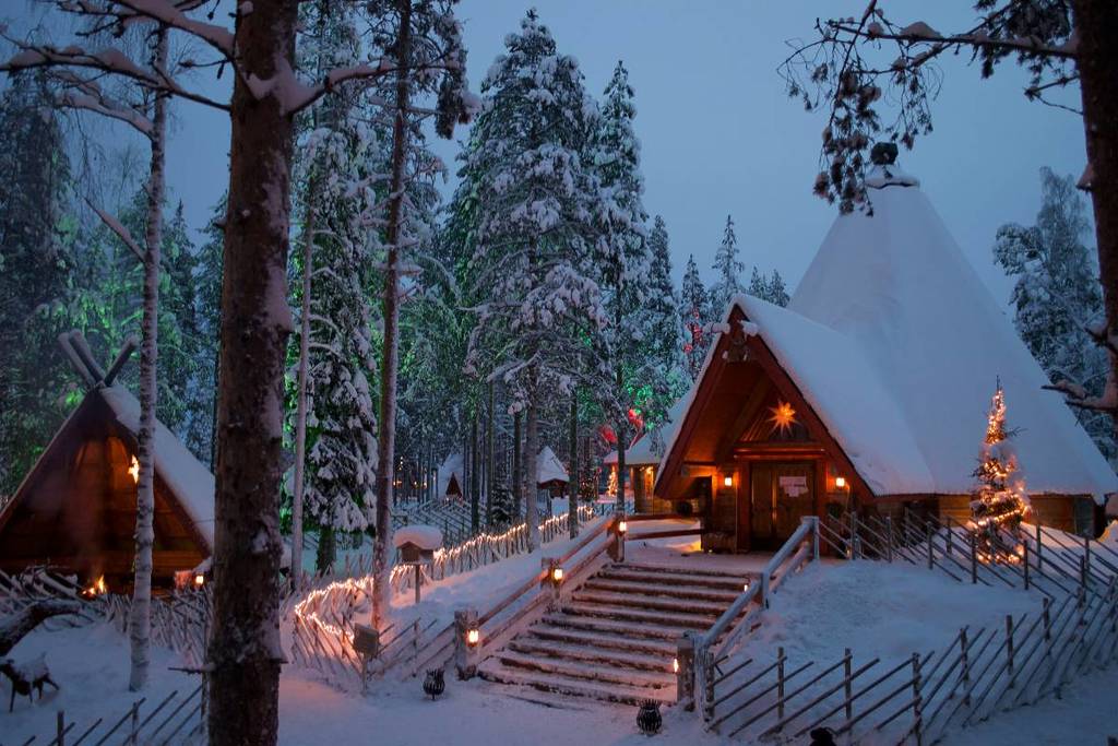 Snow-covered stairs lit by lanterns and Christmas lights and a wooden hut in the background in Rovaniemi, Lapland, Finland