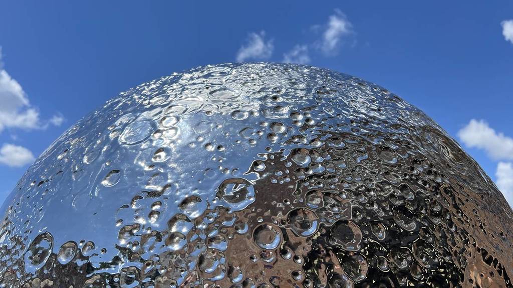 a close up of the surface of the moon as represented in a stainless steel 'mirror moon' sculpture