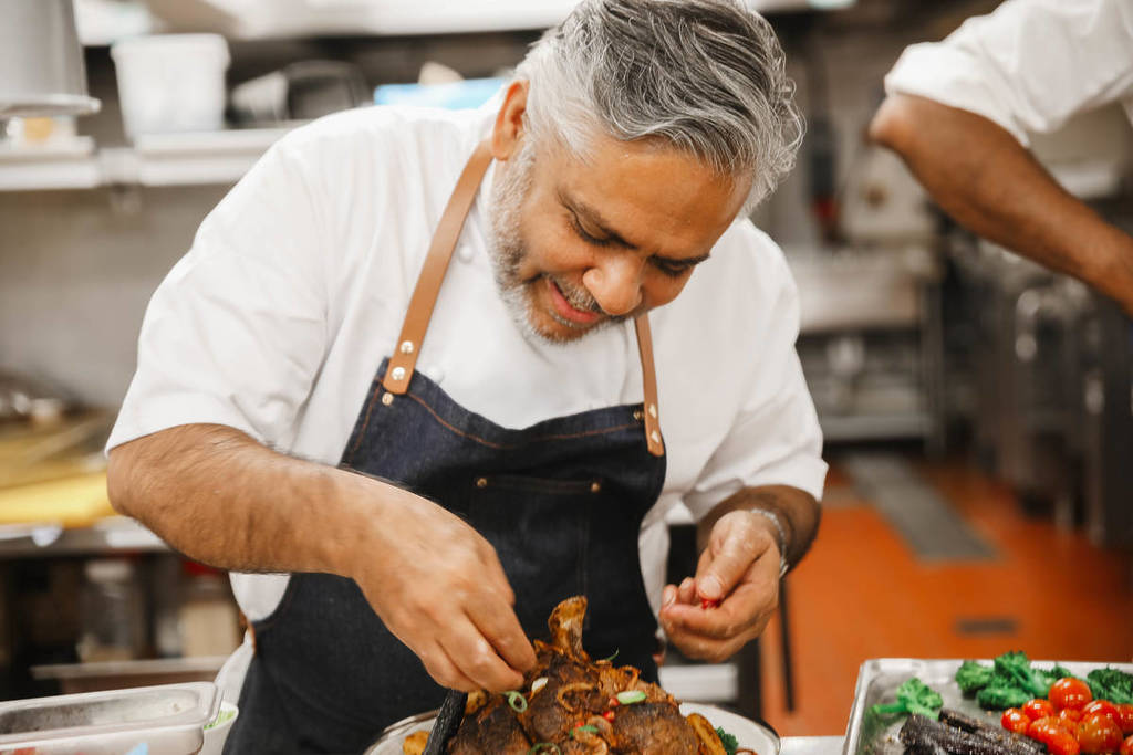 chef vivek singh adding a garnish to a dish in the kitchen
