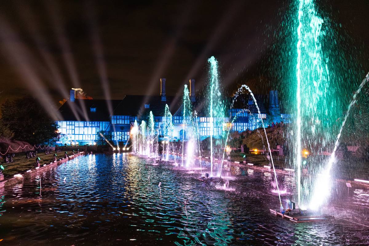 a light and water show at rhs glow wisley with enormous jets of water playing amongst lights over a lake