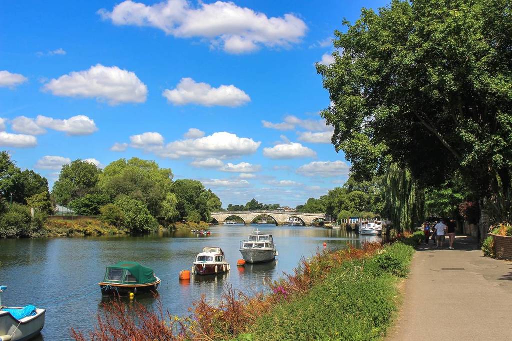 A view of Richmond Bridge and the River Thames from the Thames Path on a sunny day