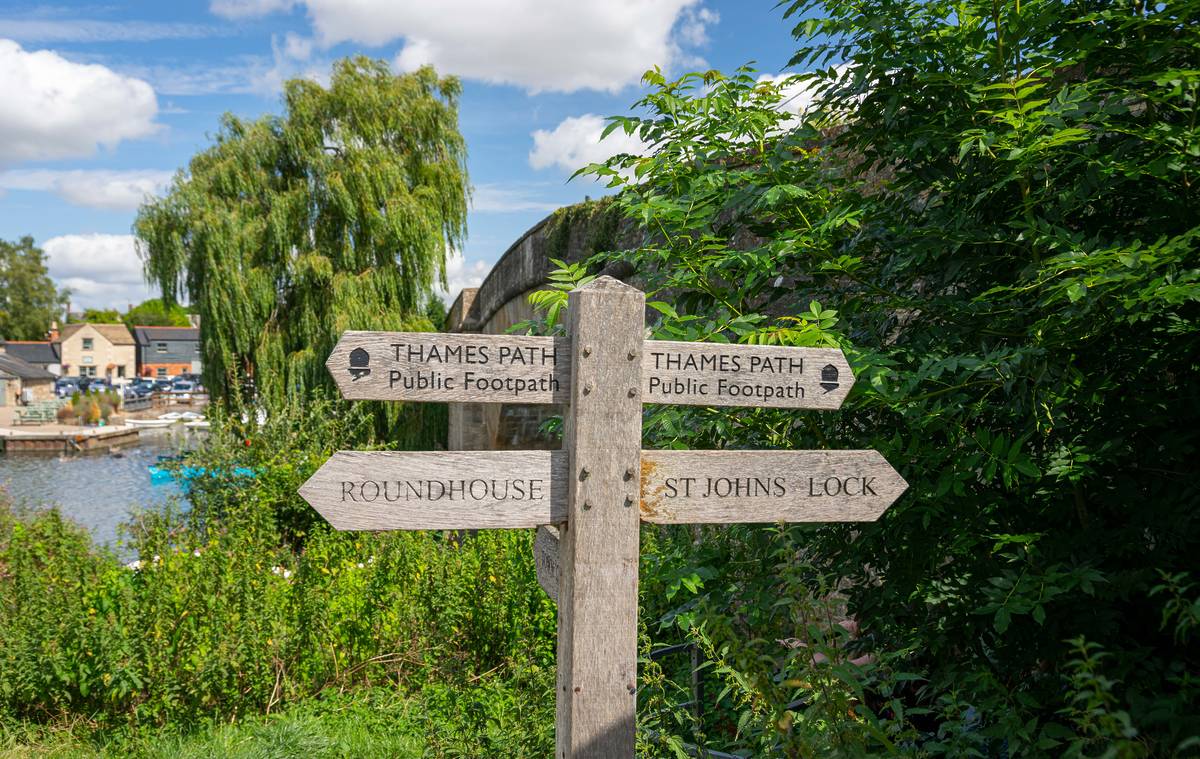A Thames Path signpost in Gloucestershire surrounded by greenery