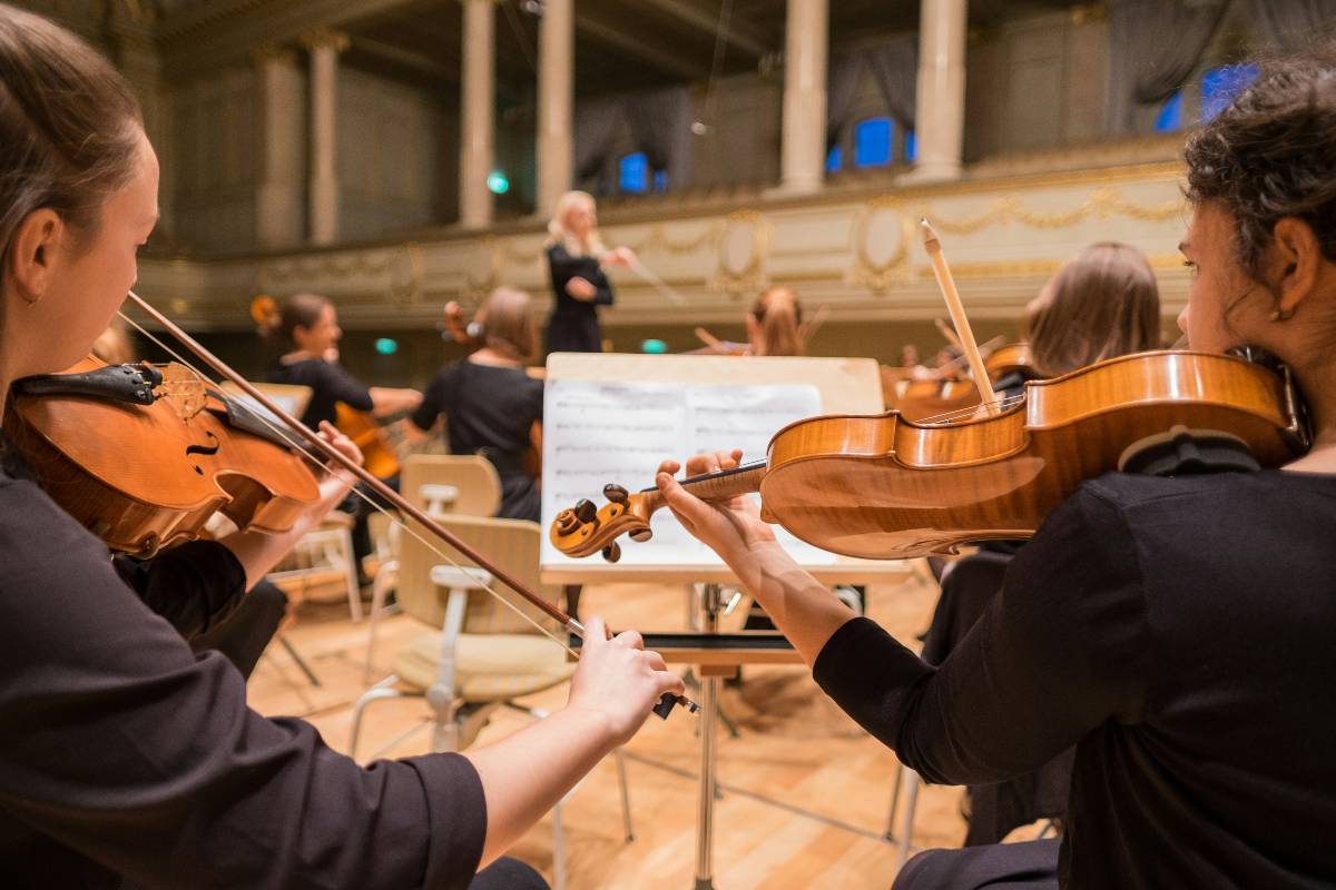 Classical musicians including violinists led by a conductor at a live classical concert