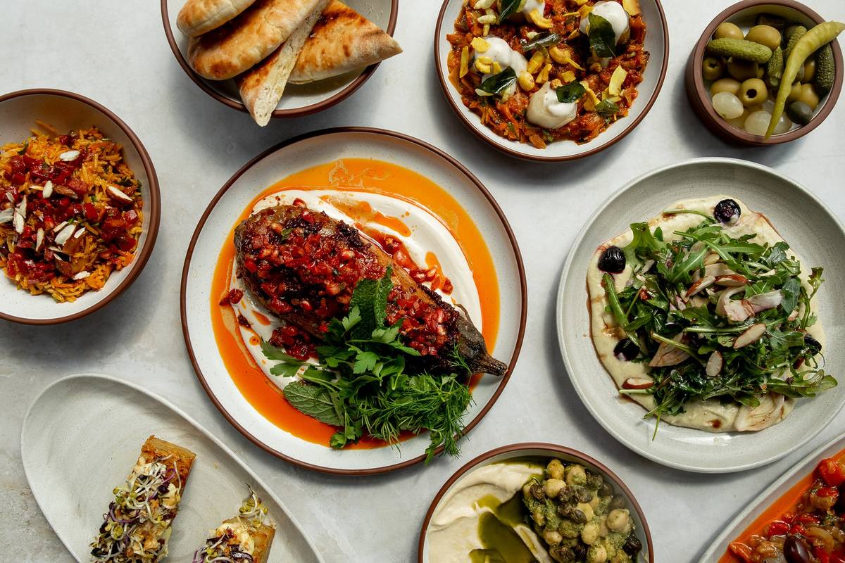 an array of vegn dishes presented on a table, with a roasted aubergine dish in place of pride at the centre