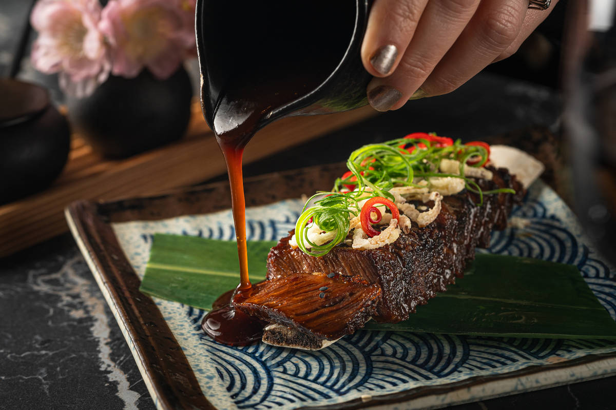 sauce being poured over a portion of sticky beef short rib