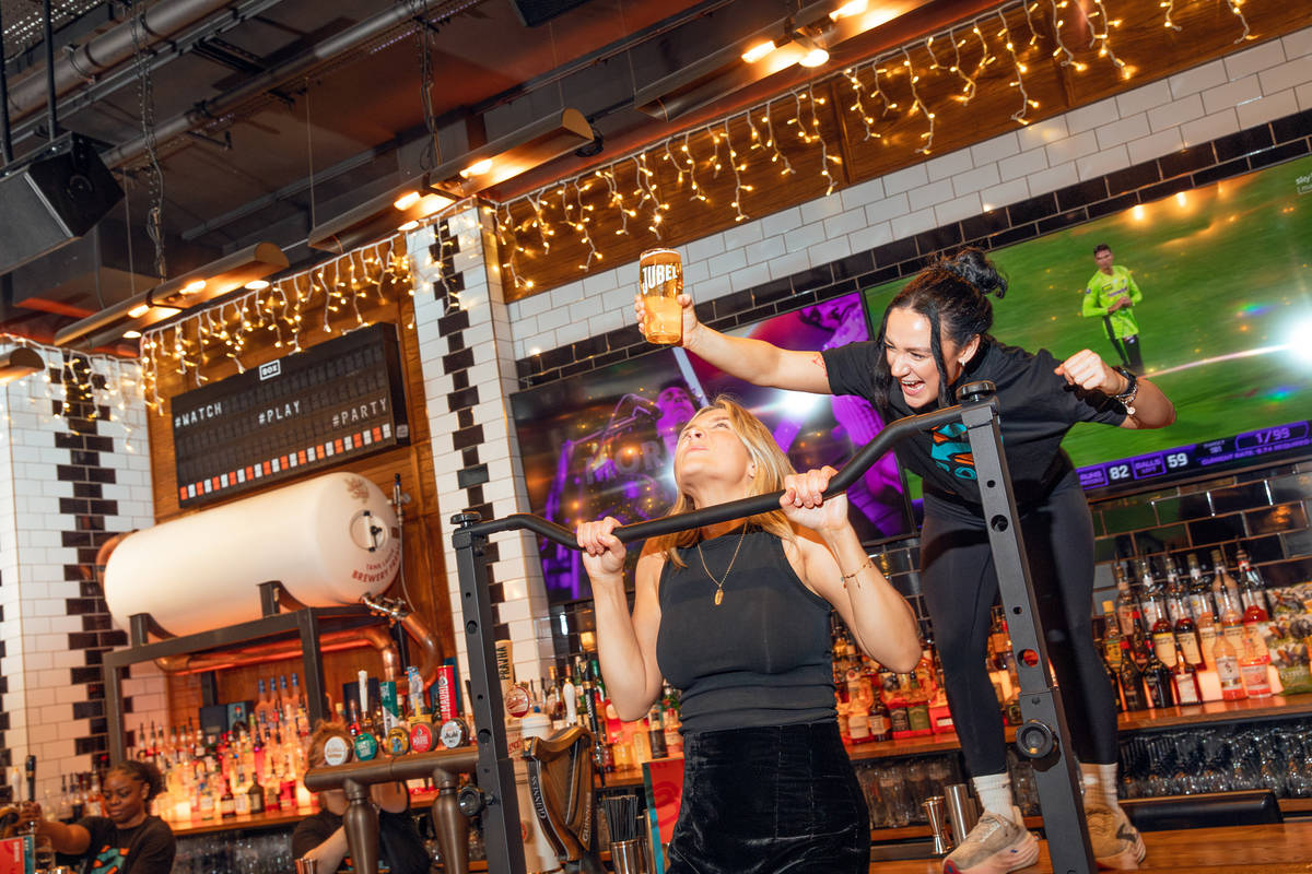 someone doing a pull up next to a bar, with someone holding a pint over their head as a tempting reward