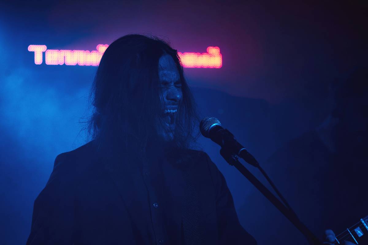 A rock singer with long hair singing into a microphone