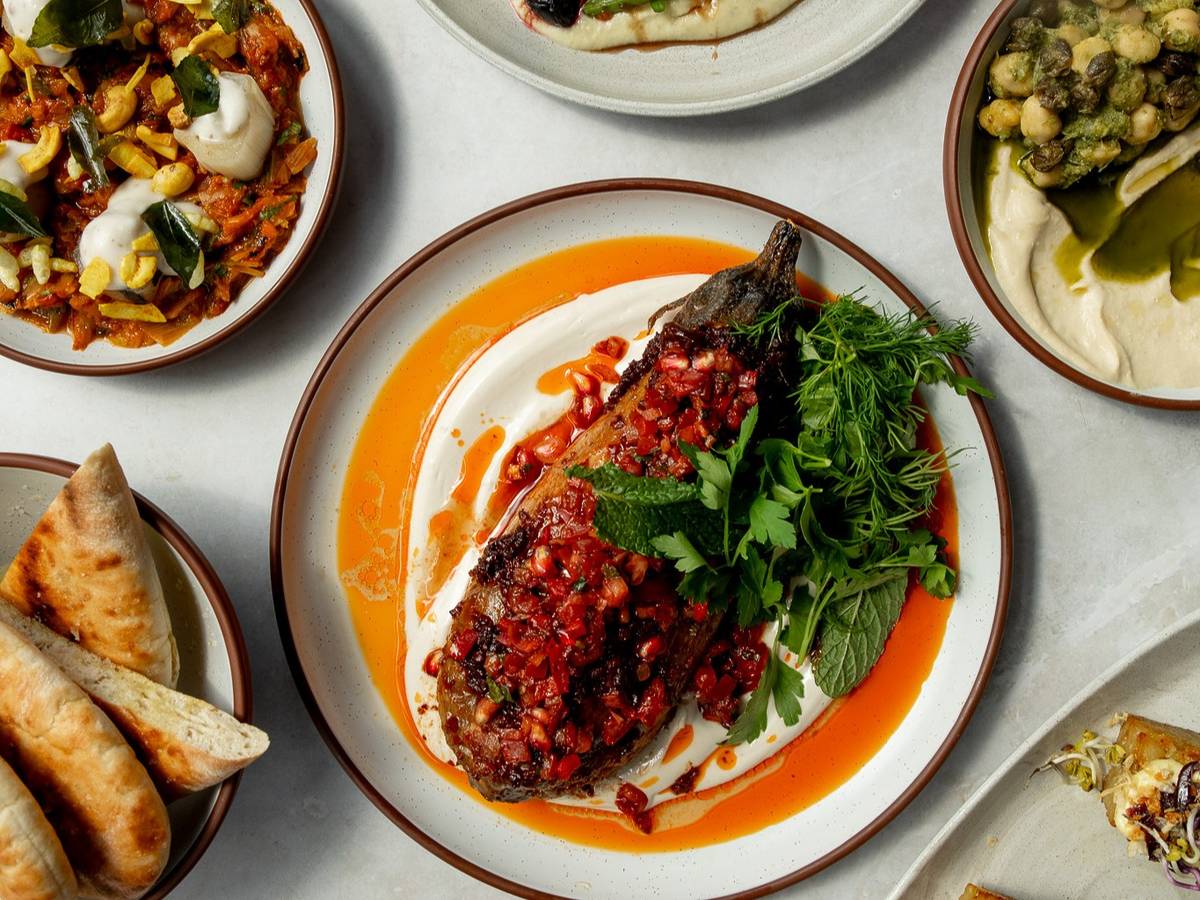 a large plate with an aubergine dish framed centre shot, with the edges of other veggie dishes visible on the sides