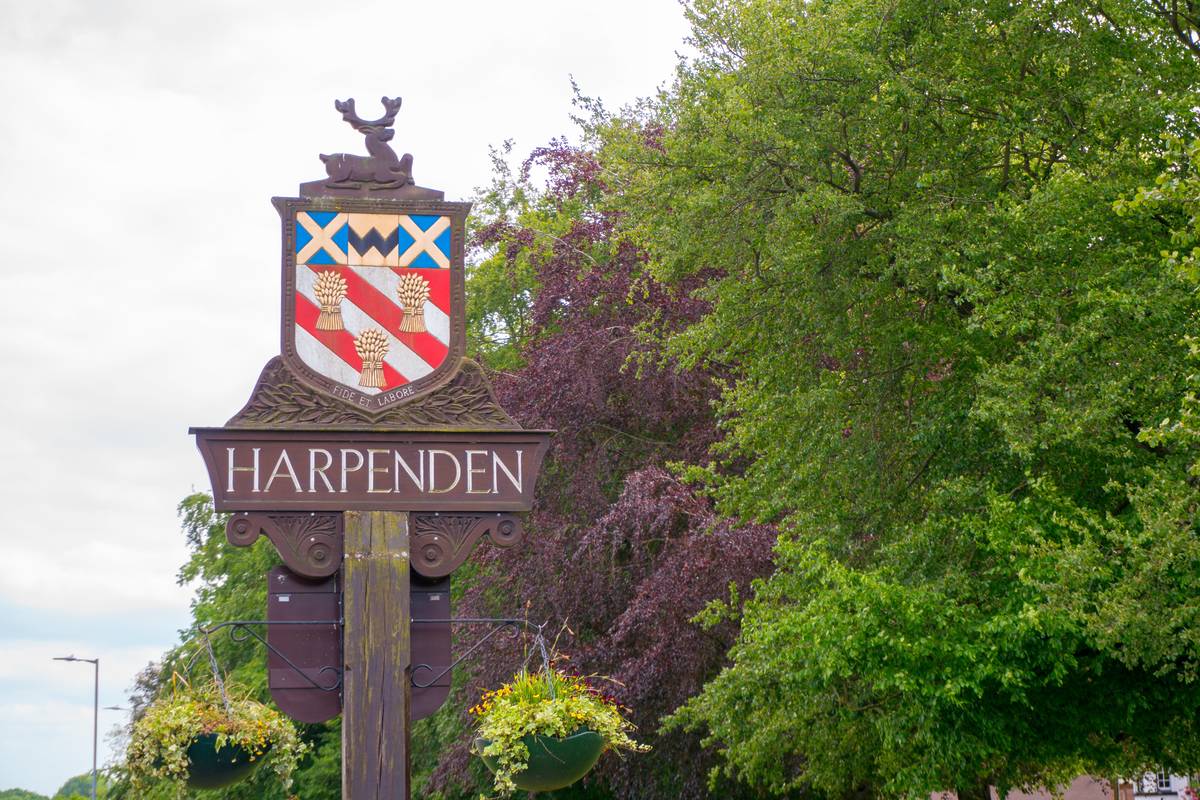 A Harpenden entry sign infront of lots of trees