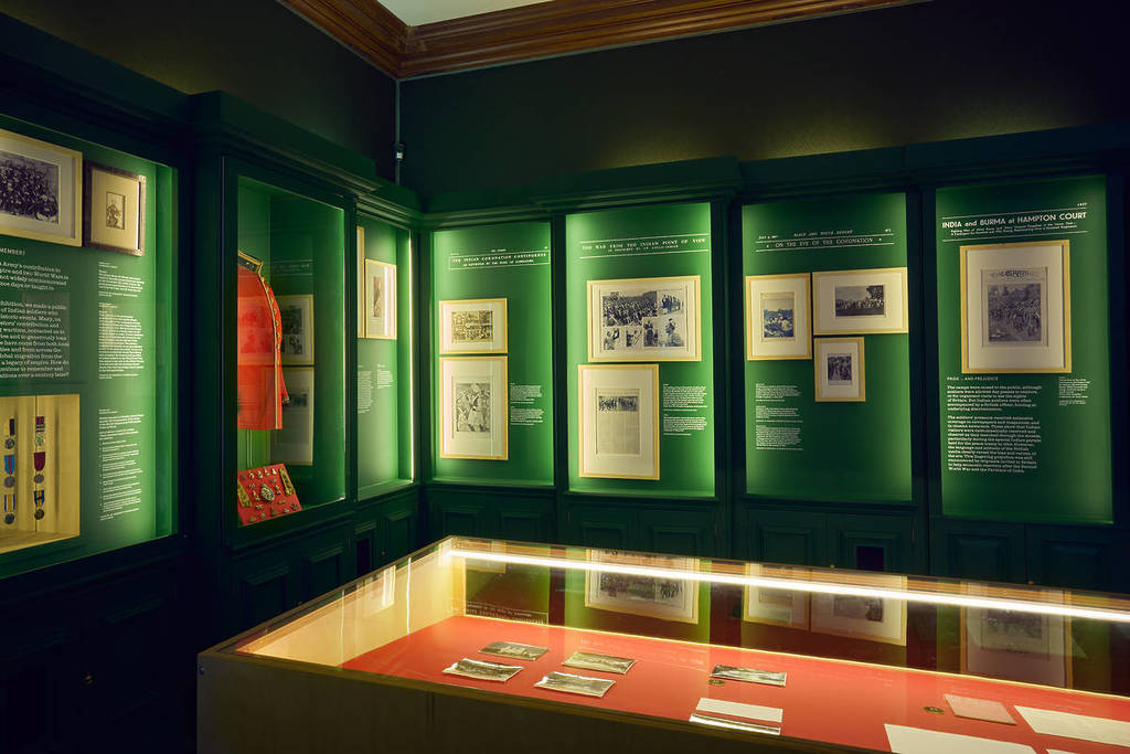 Una sala espositiva con molti oggetti dietro a vetrine su sfondo verde
