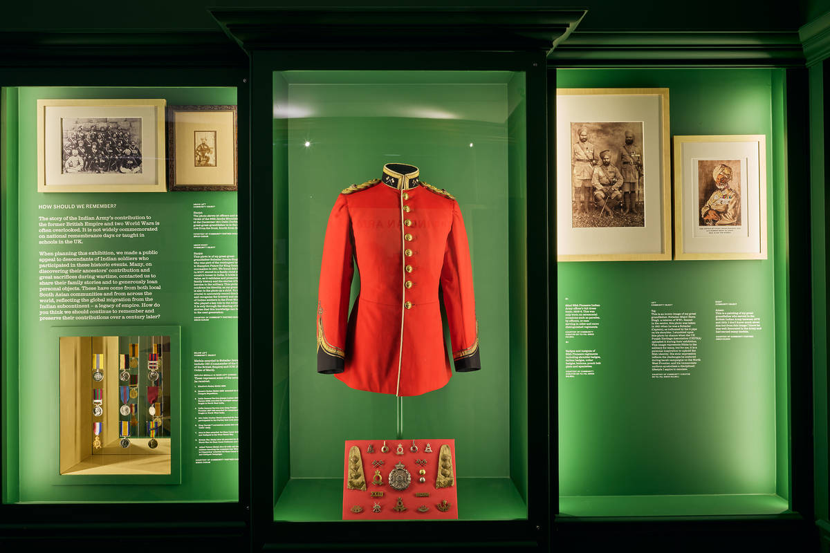 A glass cabinet in the exhibition hall with a red jacket as the centre piece and photographs on either side