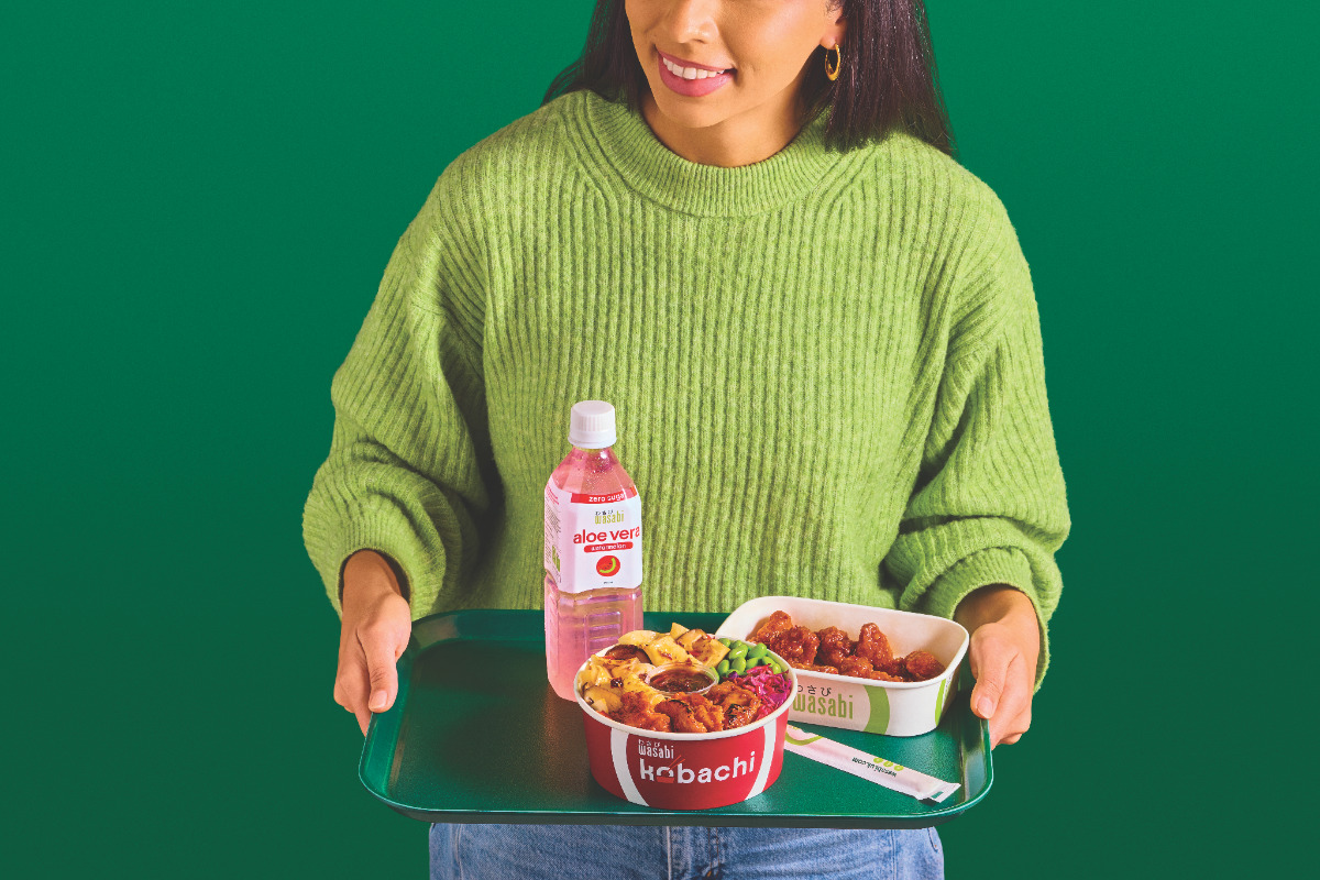 a woman in a green sweater with a tray of lunch from wasabi