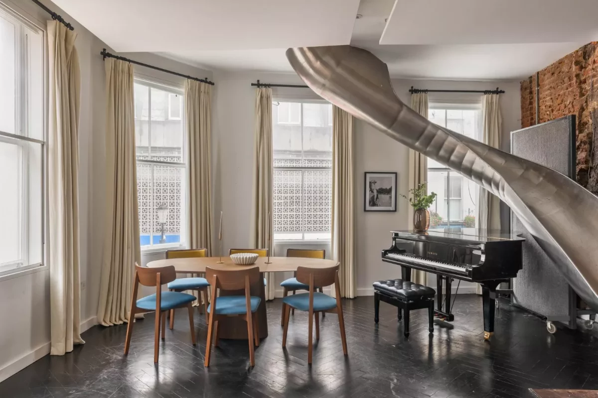 A dining area with a metal slide descending from the upper floor
