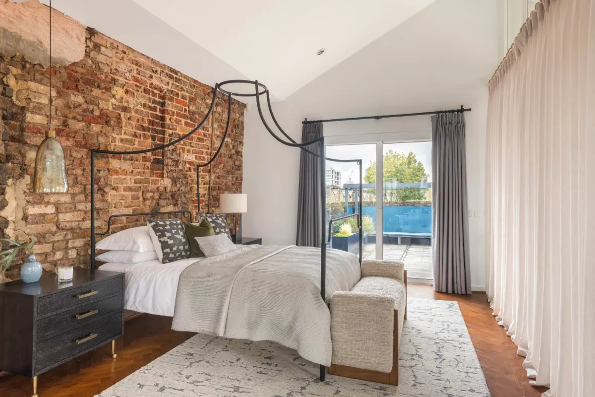 A bedroom with a bed against an exposed brick wall