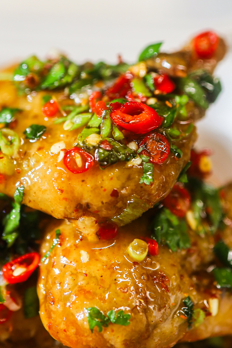 glistening saucy thai style fried chicken wings with chilli slices and herbs
