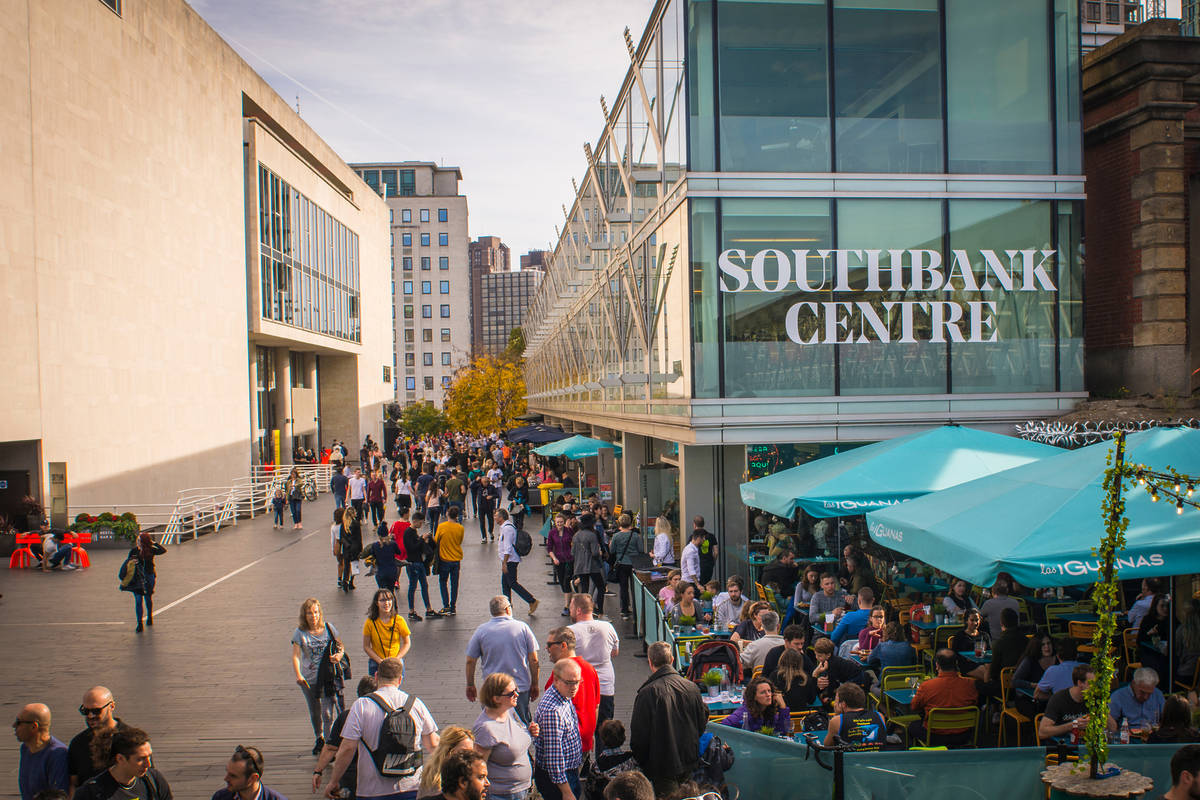 the exterior of the southbank centre with people milling around and sitting at tables at a connected bar
