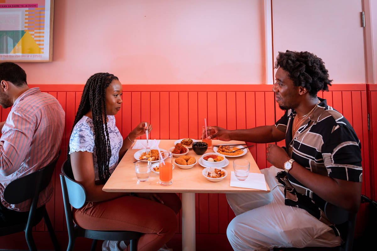 two people enjoying a meal together in a pink hued restaurant