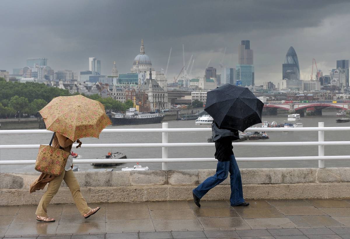 people walking in london during a storm with umbrellas covering their face