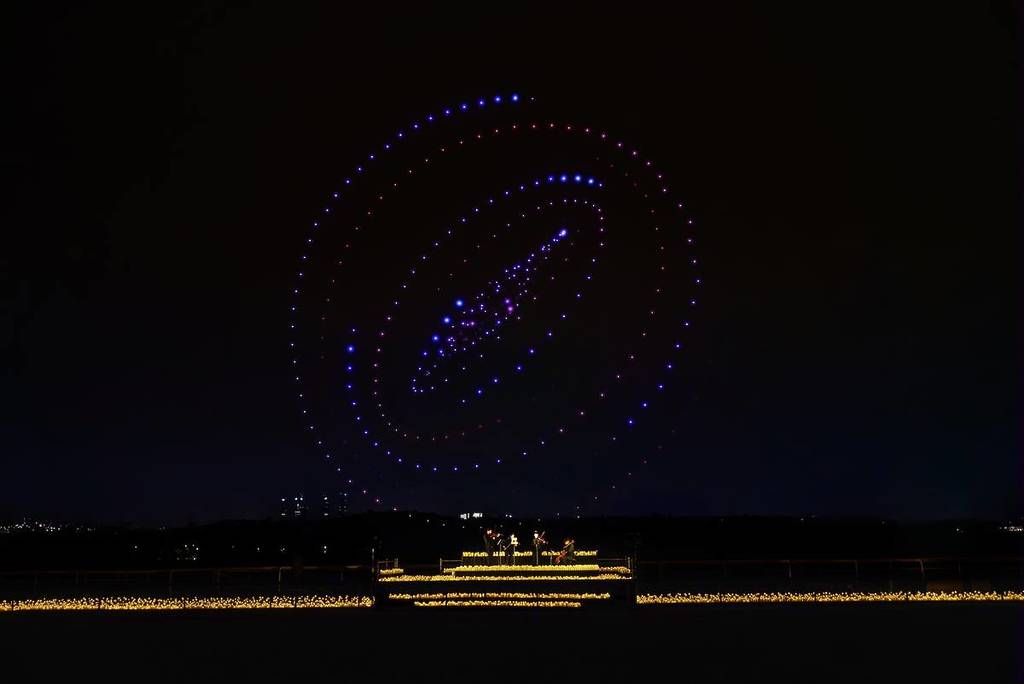 a swirling image created by hundreds of drones, illuminates the sky over a string quartet performing by candlelight at the DroneArt Show