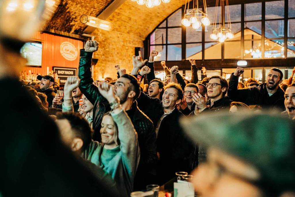 a lively room full of people watching a sports match and cheering