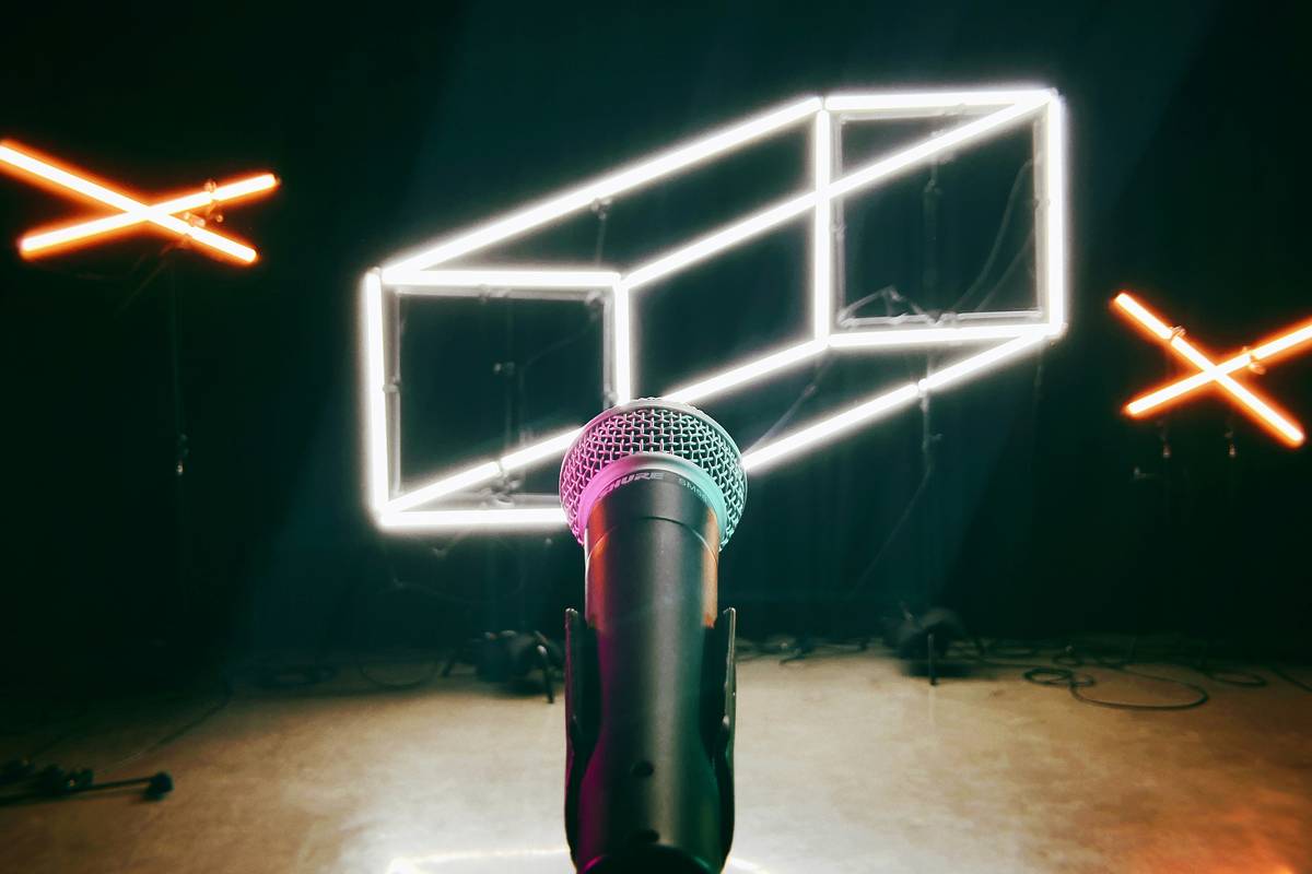 Microphone on stage with neon signage.