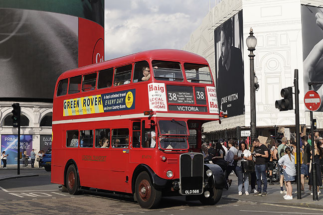 People queueing to get on a vintage red bus in Piccadilly Circus