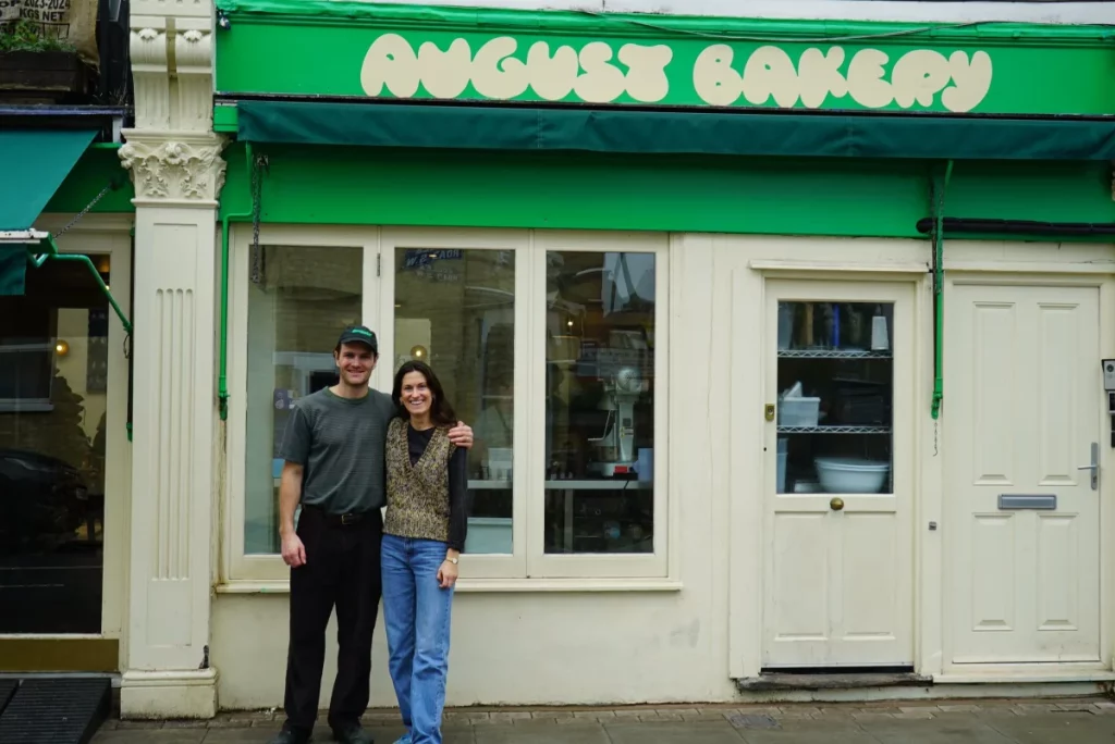 Os proprietários da August Bakery ficavam do lado de fora da padaria, um edifício branco com uma placa verde brilhante