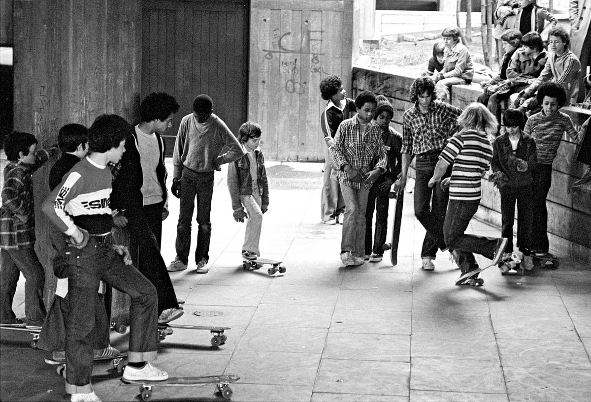 a group of skateboarders standing around in the undercroft skate space