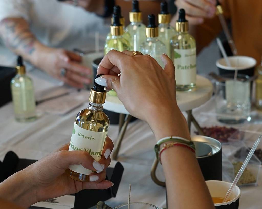 Una mujer sostiene una botella con una fragancia en un taller de fabricación de velas.