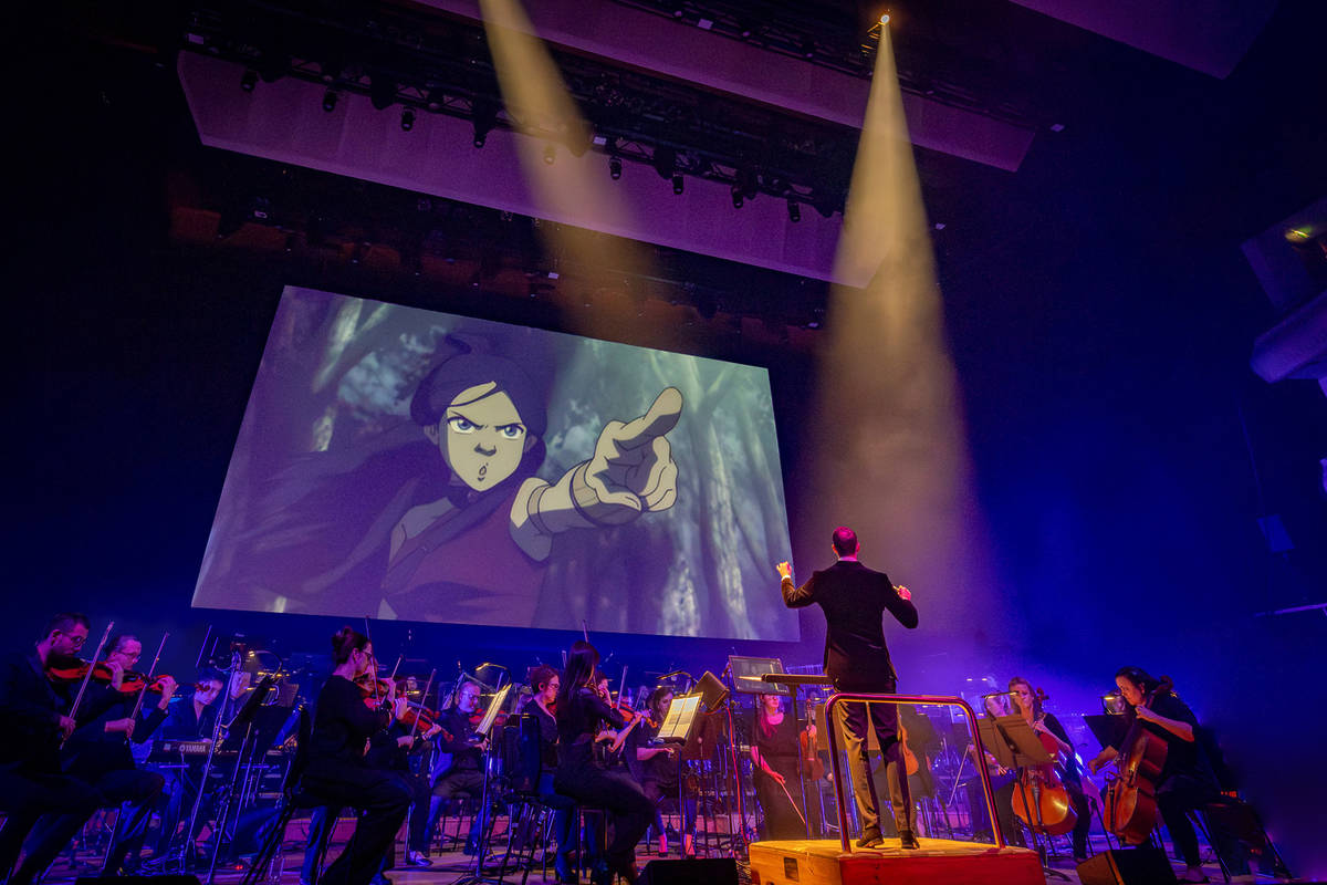a live orchestra on stage under a screen showing a scene from avatar the last airbender