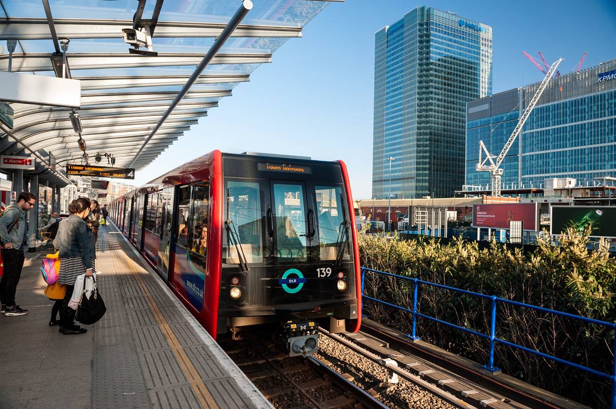 A DLR train pulling into the platform at Poplar station