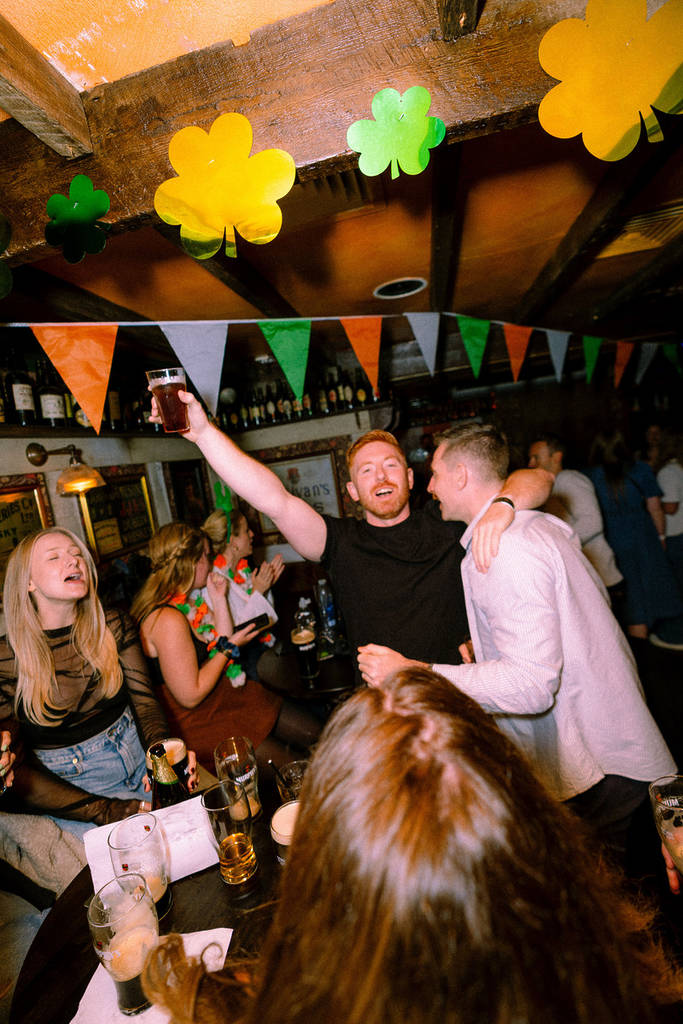 people in a pub decorated with irish bunting, celebrating st patricks day