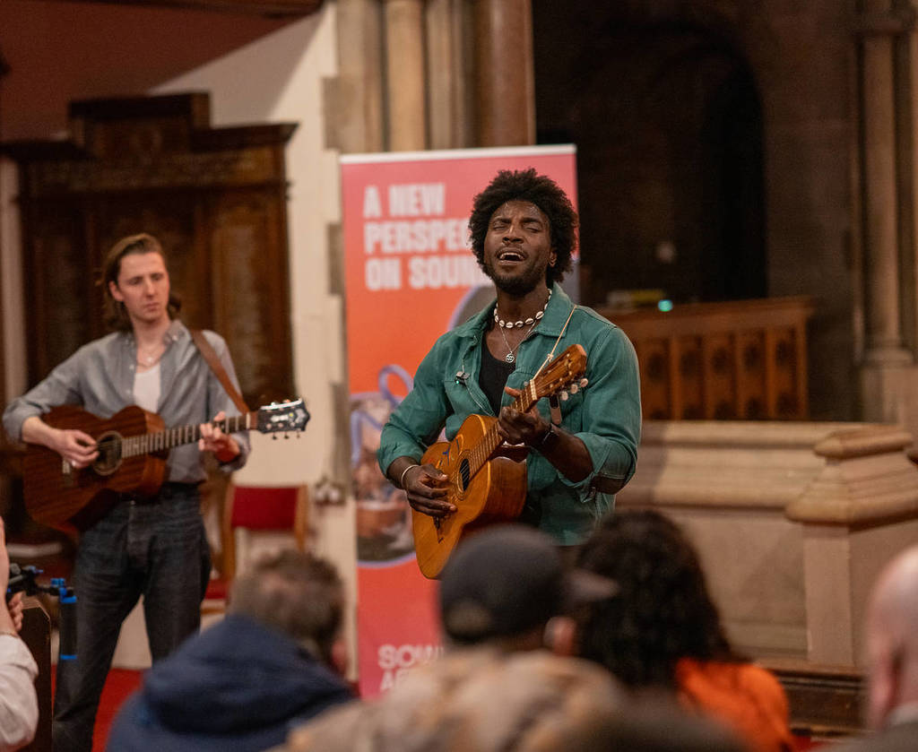 Musician Caleb Kanule performing at an unplugged audio-inclusive gig as part of Hackney Hearing Wellness Week