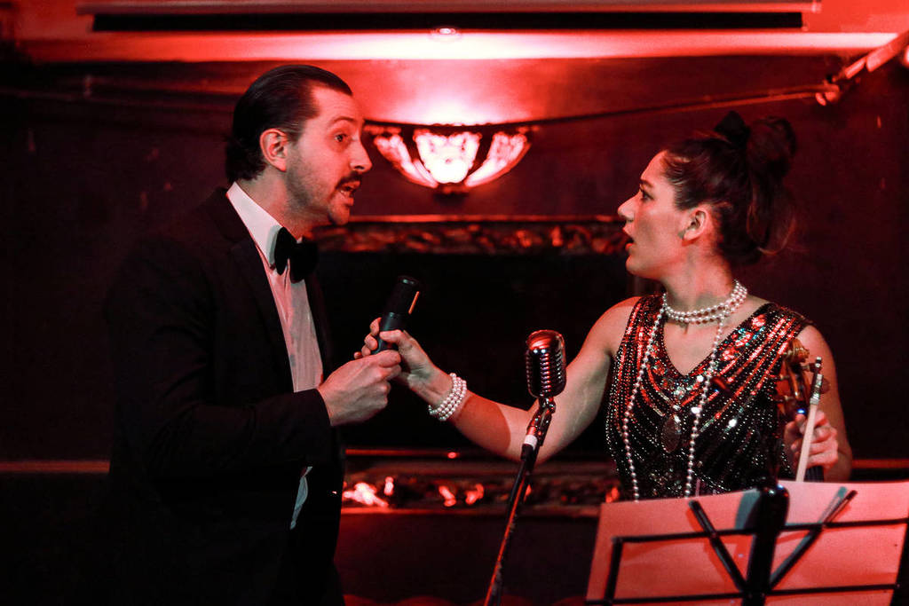 two performers dressed in throwback 1940s clothing interacting at a murder mystery