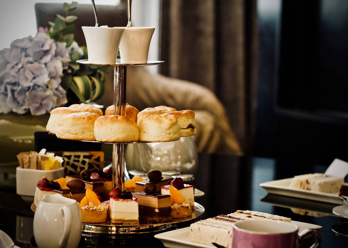 Afternoon tea in London featuring scones, clotted cream, jam, cakes and tea