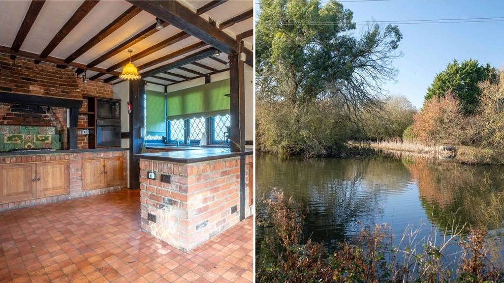 uma cozinha de quinta com vigas de madeira no teto e ilha de tijolos (à esquerda), um lago rodeado por vegetação (à direita)