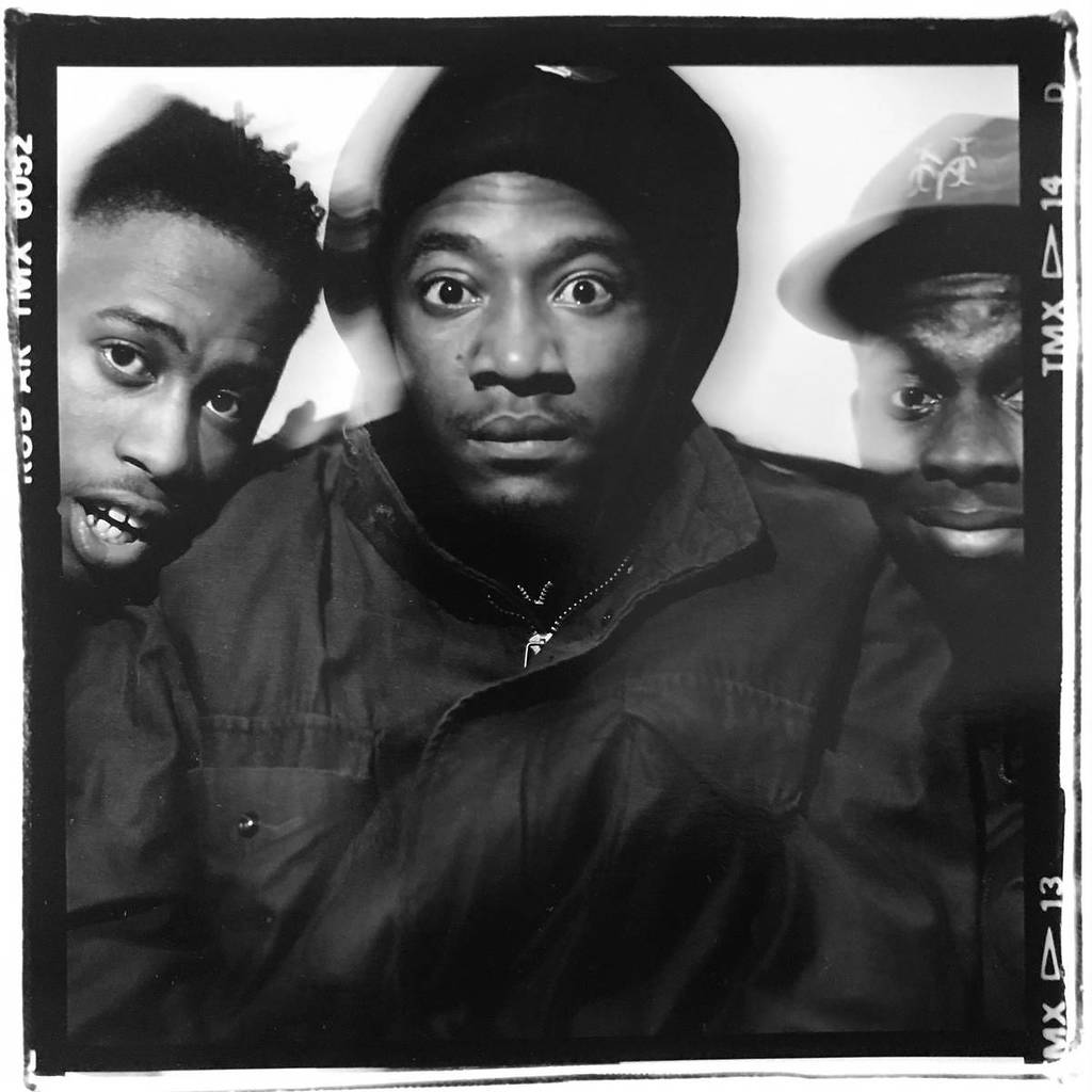 a slightly blurry photo of the members of a tribe called quest that looks almost like they're vibrating