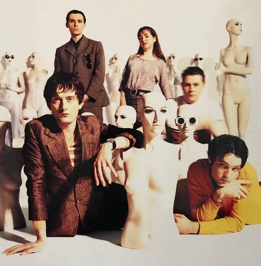 the members of Pulp posing for a photo, surrounded by mannequins in various states of disrepair