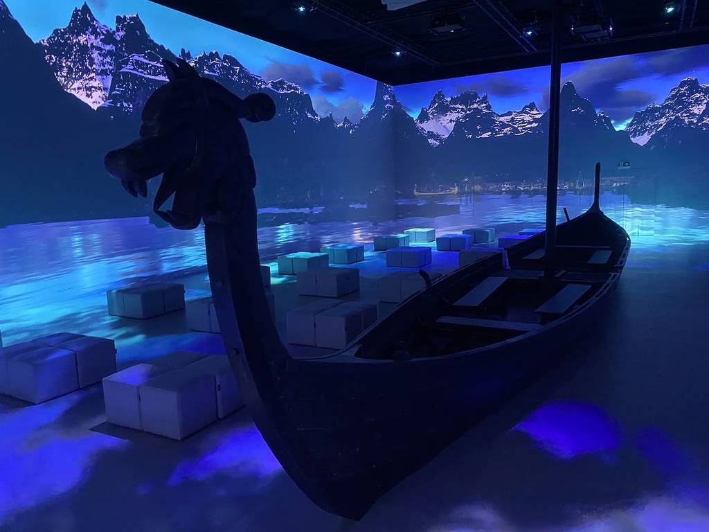 a longship recreation in a 360-degree room depicting mountains and water at at Vikings: The Immersive Experience