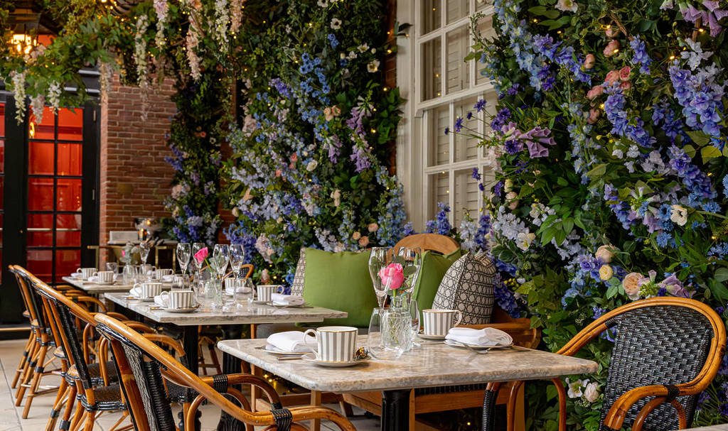 Mesas dispostas no interior do Dalloway Terrace, com paredes cobertas de flores primaveris