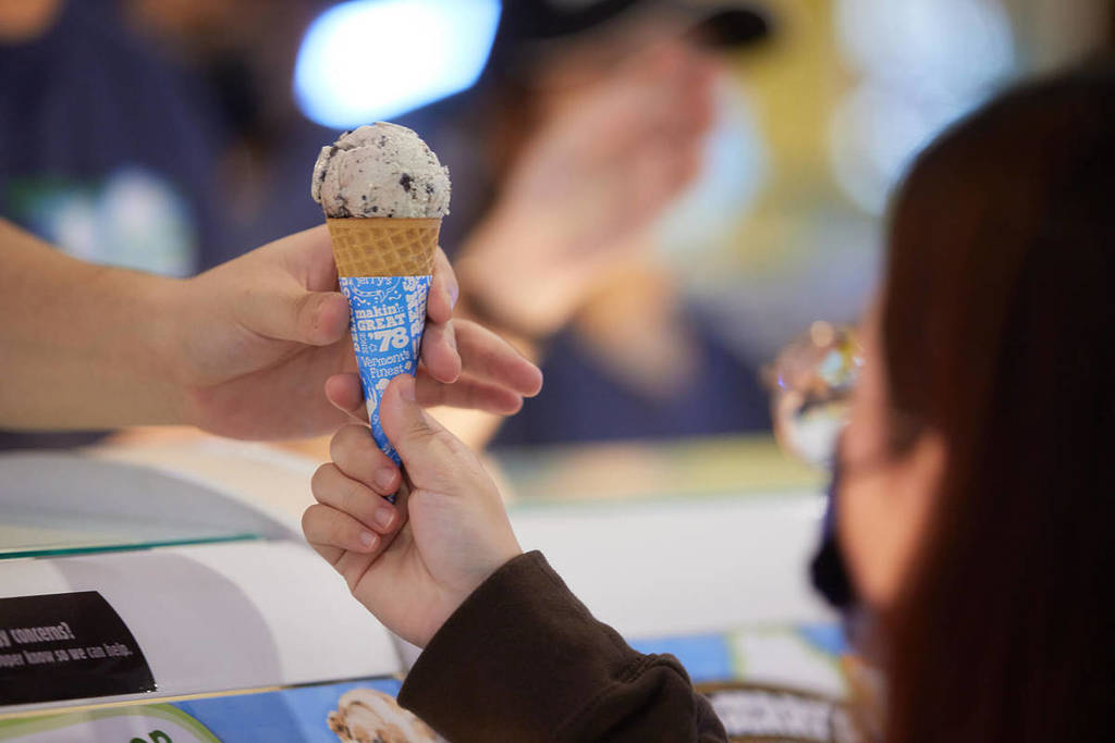 Jemandem wird eine Waffel mit einer Kugel Choc-Chip-Eis gereicht