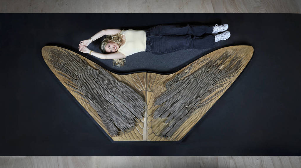 Jemand liegt neben einem riesigen Fossil des Schwanzes eines Unterwasser-Raubtiers