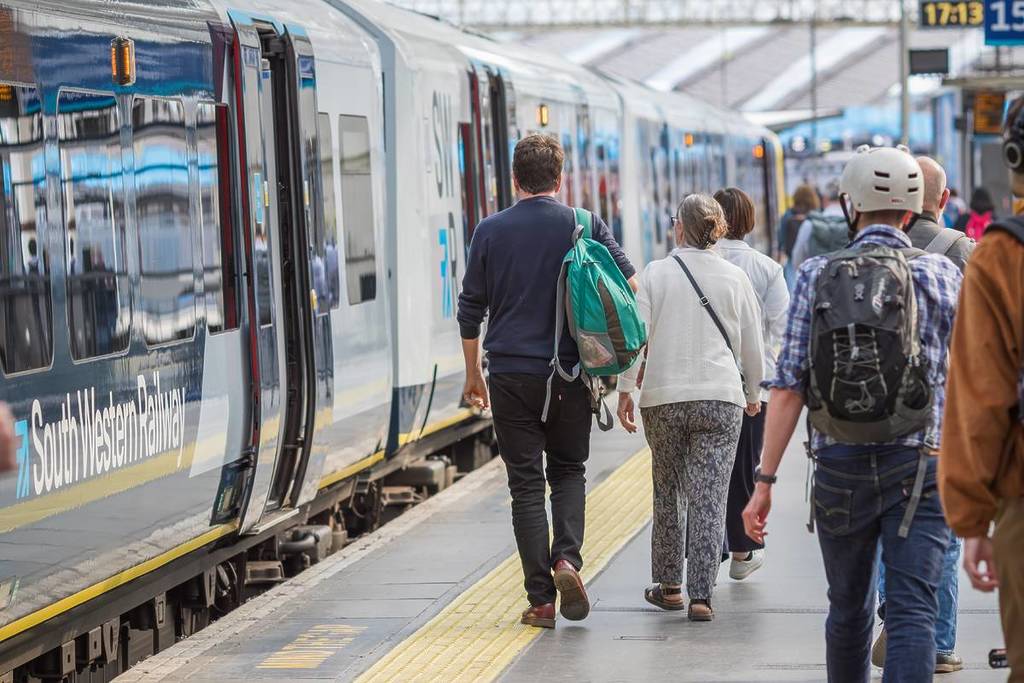 London, Großbritannien - 24. Mai 2024 - Eine Menschenmenge geht am Bahnhof London Waterloo auf einen Zug der South Western Railway zu
