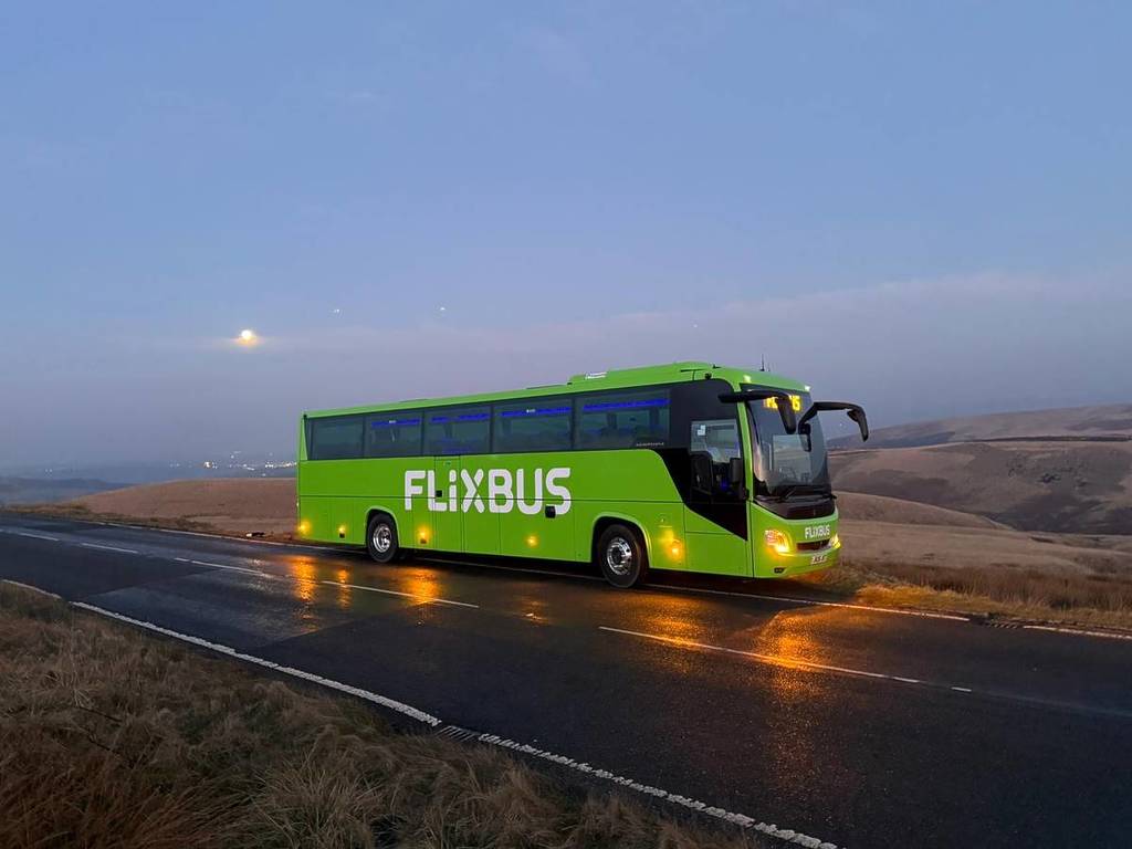 Ein grüner Flixbus-Bus fährt eine leere Straße entlang