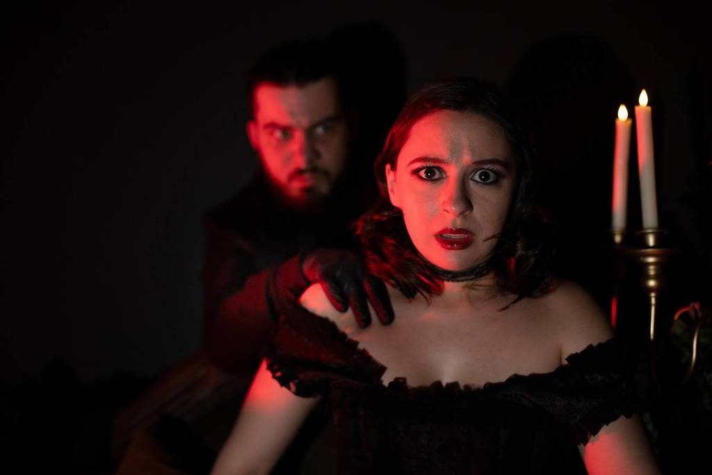 Ein Serienmörder unter roten Lichtern, der die Schulter eines Mädchens bei Serial Killers Speakeasy hält