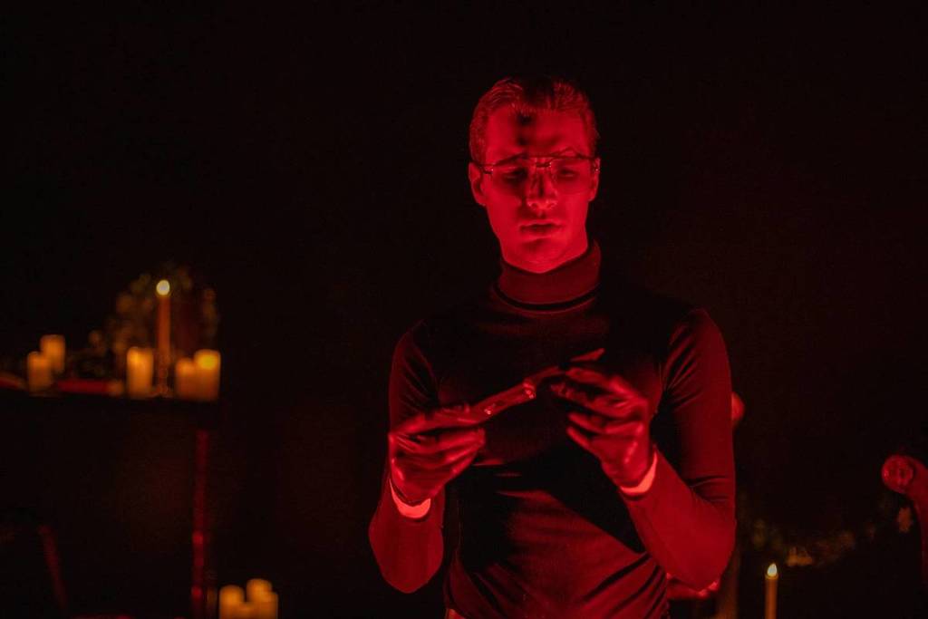 Ein Schauspieler, der Jeffrey Dahmer spielt, hält unter rotem Licht bei der Cocktail-Erfahrung „Serial Killer Speakeasy“ ein Messer in der Hand