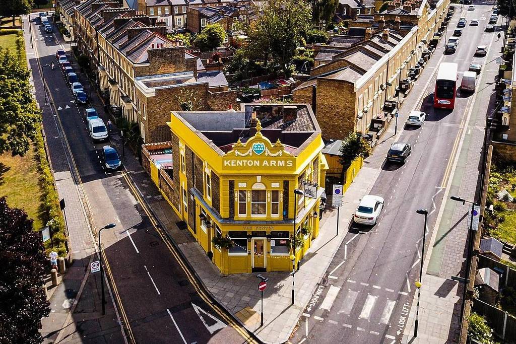 Eine Luftaufnahme des charmanten Eckpubs The Kenton, der durch seine leuchtend gelbe Farbgebung auffällt